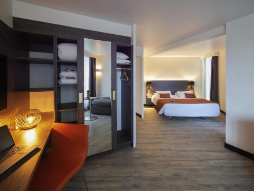 une chambre d'hôtel avec un lit et un grand miroir dans l'établissement Novotel La Grande Motte Golf, à La Grande Motte