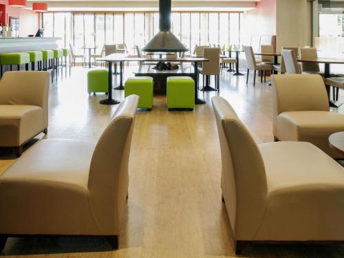 a waiting room with chairs and a table and tables at ibis Styles Louvain-la-Neuve Hotel and Events in Louvain-la-Neuve