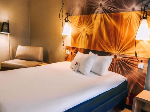 a hotel room with a bed and a chair at ibis Hotel Frankfurt Airport in Kelsterbach