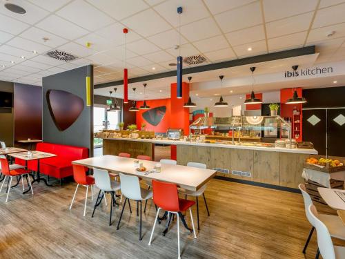 a restaurant with tables and chairs and a kitchen at ibis Hotel Frankfurt Airport in Kelsterbach