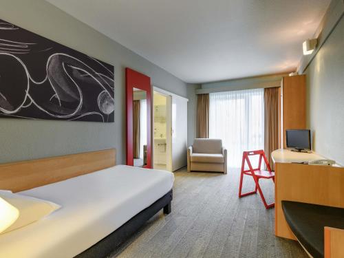 a room with a bed and a desk and a television at ibis Luebeck City in Lübeck