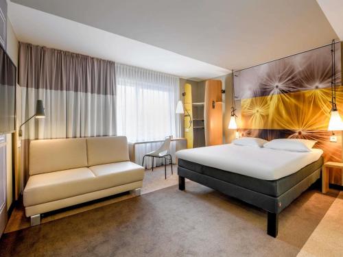 a hotel room with a bed and a couch at ibis Luebeck City in Lübeck