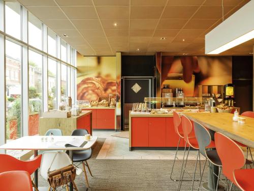 a kitchen with red cabinets and a table and chairs at ibis Luebeck City in Lübeck
