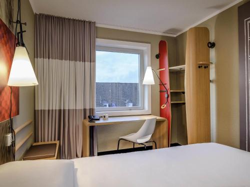 a room with a bed and a desk and a window at Ibis Münster City in Münster