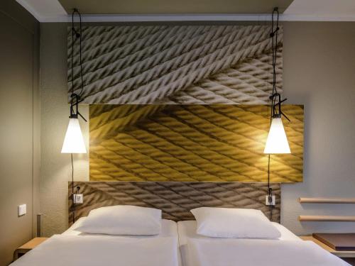 two beds in a room with a painting on the wall at Ibis Münster City in Münster