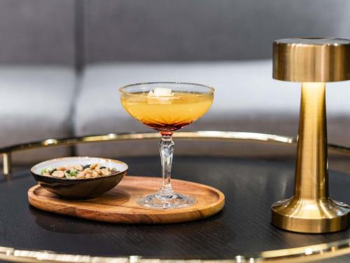 a drink in a glass on a table with a bowl of nuts at Mercure Paris Gare De Lyon TGV in Paris
