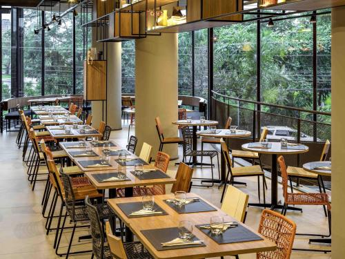 a dining room with tables and chairs and windows at ibis Sao Paulo Barra Funda in Sao Paulo