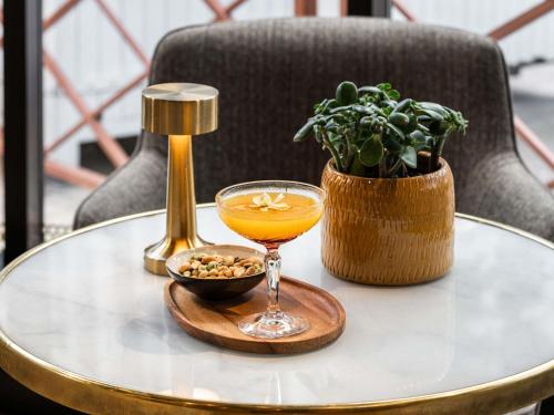 a glass of orange juice on a table with a plant at Mercure Paris Gare De Lyon TGV in Paris