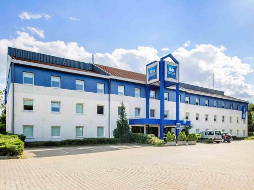 a large white and blue building with a parking lot at ibis budget Dresden Kesselsdorf in Wilsdruff