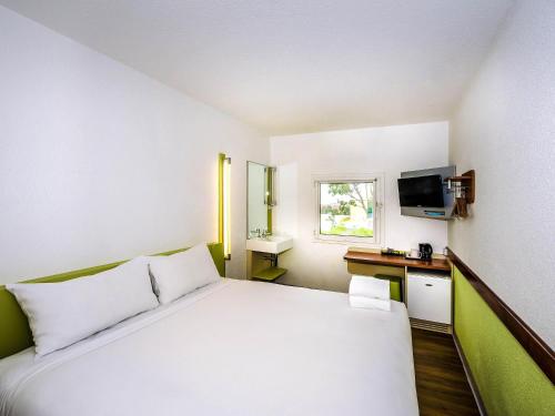 a hotel room with a white bed and a television at ibis Budget - St Peters in Sydney