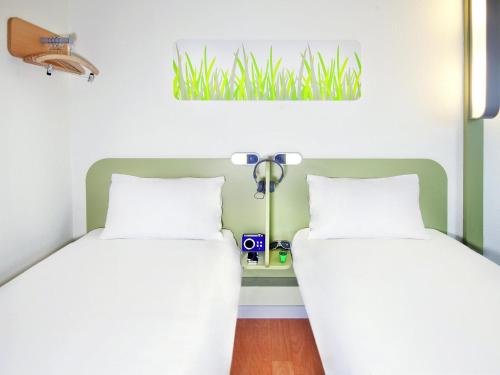 a bedroom with two beds and a plant on the wall at ibis budget Augsburg Gersthofen in Augsburg