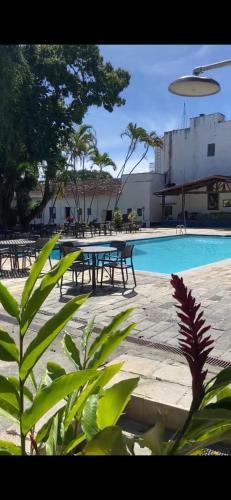 a swimming pool with tables and a picnic table at Mara Palace Hotel in Vassouras
