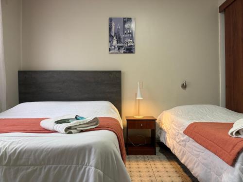 a bedroom with two beds and a table with a lamp at Hotel Boutique Parque Brasil in Antofagasta