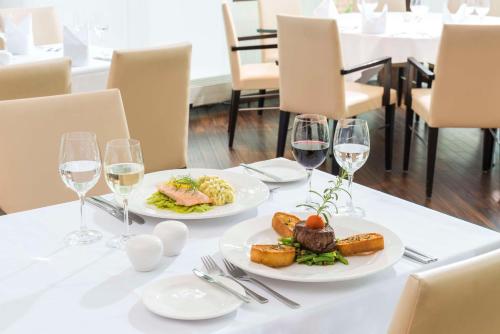 a table with two plates of food and wine glasses at NH Dresden Neustadt in Dresden