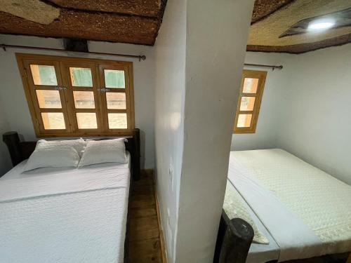 two twin beds in a room with two windows at Volcanoes Over View Safaris & Camp in Nyarugina