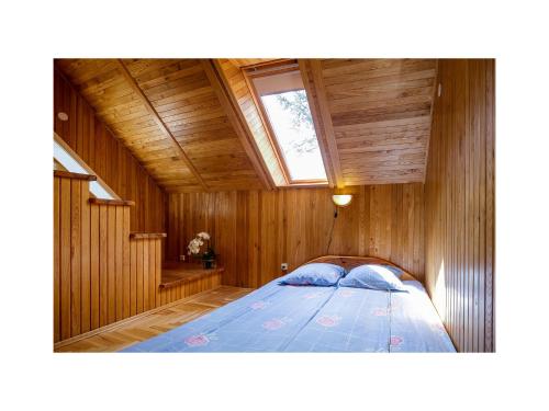 um quarto com uma cama num quarto de madeira em Forest Cottage em Neringa