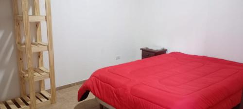 a bedroom with a red bed and a ladder at Cabaña Los Angeles in Villa General Belgrano
