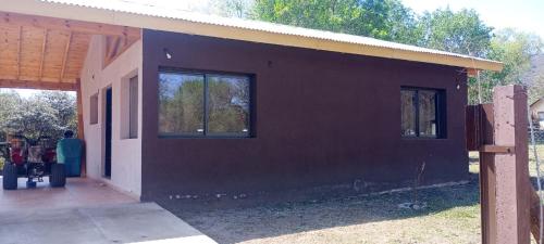a house with a black wall and two windows at Cabaña Los Angeles in Villa General Belgrano