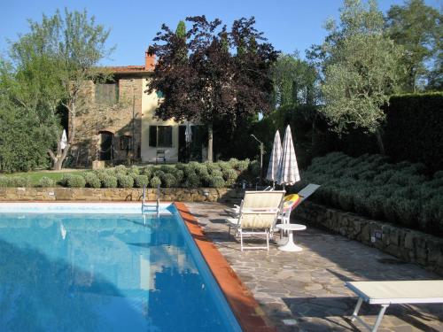 a swimming pool with a table and chairs and a house at Agriturismo Podere Asciana in Bucine