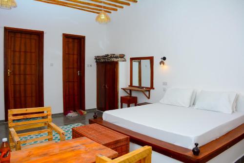 Un dormitorio con una gran cama blanca y una mesa. en Sailorvilla and apartments, en Jambiani