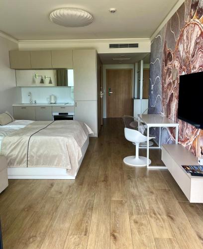 a bedroom with a bed and a desk and a television at Seaside Park apartamenty prywatne z widokiem na morze in Kołobrzeg