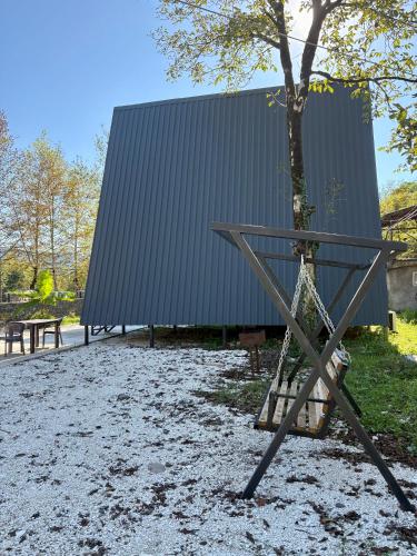 a metal structure next to a tree and a building at Wooden House Martvili in Martvili