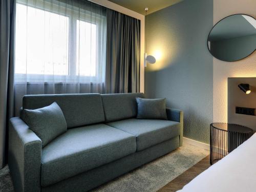 a living room with a couch and a window at Novotel Zurich City West in Zürich