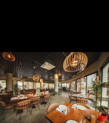 a restaurant with wooden tables and chairs and chandeliers at Caesar Resort Spa Long Beach 