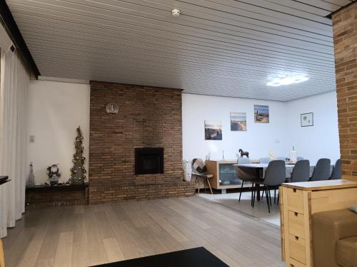 a living room with a fireplace and a table and chairs at 't Calmeyntje in De Panne