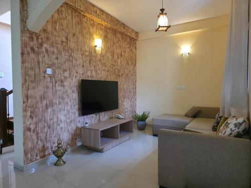 a living room with a couch and a tv on a brick wall at Vithum Villa - Kandy Home with Balcony View and Parking in Kandy