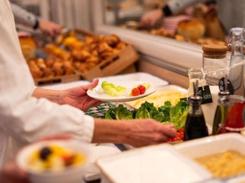 a person holding a plate of food at a buffet at ibis Lyon Centre Perrache in Lyon