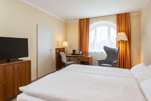 a hotel room with a bed and a flat screen tv at NH Wien Belvedere in Vienna