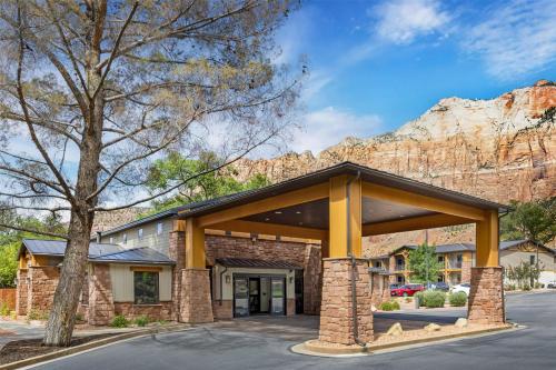 a large brick building with a mountain in the background at Best Western Plus Zion Canyon Inn & Suites in Springdale