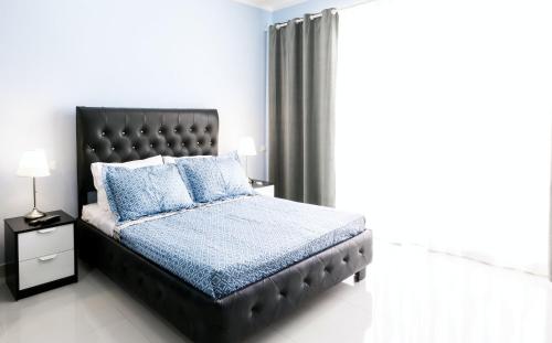 a bedroom with a black bed with blue pillows at LA PERLA STUDIOS with ROOFTOP POOL and SPA - PLAYA LOS CORALES in Punta Cana