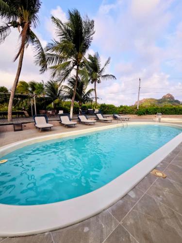 a large swimming pool with chairs and palm trees at Pousada Liberty Noronha in Fernando de Noronha