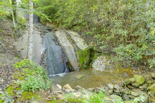 a waterfall in the middle of a forest at Remote Home with Deck and Grill in Scenic Tuckasegee! in Tuckasegee