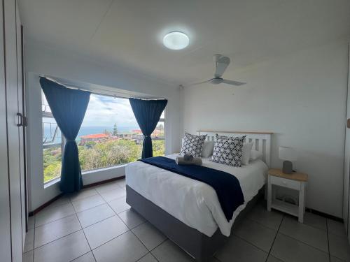 a bedroom with a bed and a large window at Dana Bay Beach House in Mossel Bay