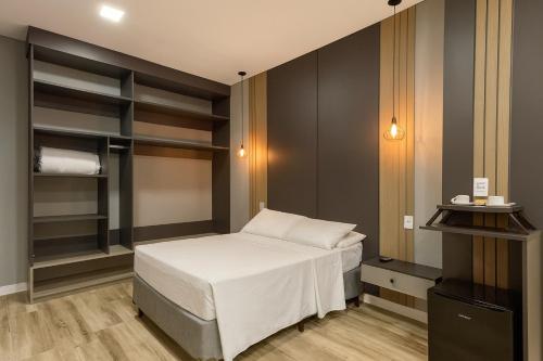 a small bedroom with a bed and shelves at Eleganz Suítes Exclusive Centro in Gramado