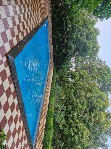 a swimming pool with trees next to a building at Quietude in Khalapur