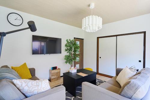 a living room with a couch and a clock on the wall at IZUMI House in Yachimata