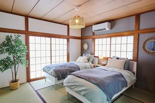 a bedroom with two beds and a potted plant at IZUMI HOUSE - 成田空港から車で22分 - 最大8名 - 駐車場2台完備 - Switch有 - 10月28日以降ペット歓迎 in Yachimata