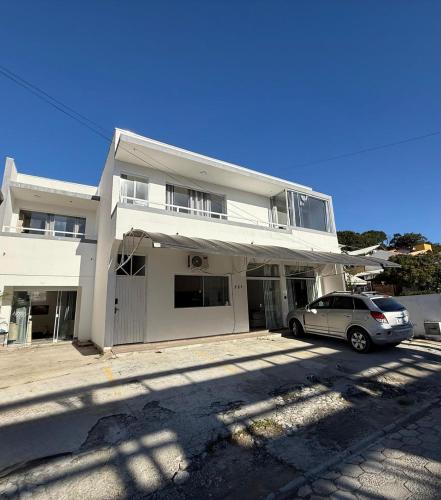 a white house with a car parked in front of it at Residencial Europa in Bombinhas