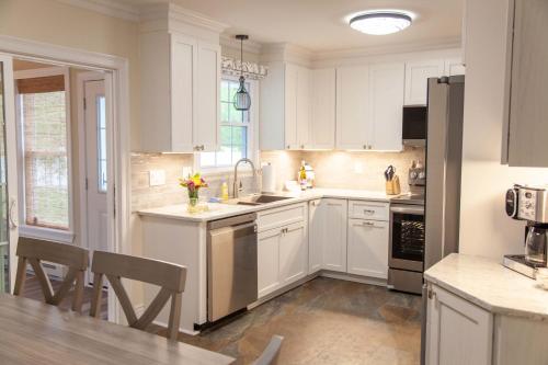 a kitchen with white cabinets and a sink and a table at Canalside Cottage 3BR Lake Access Dock Fire Pit in Waterloo