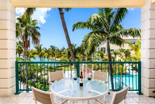 a table and chairs on a balcony with palm trees at 2 Bdrm Pool Marina View at The Yacht Club E12 in Providenciales