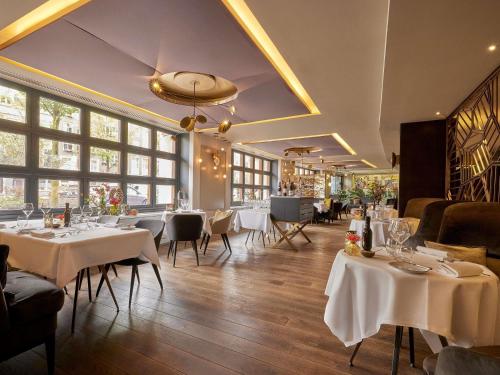 a restaurant with white tables and chairs and windows at Sofitel Legend The Grand Amsterdam in Amsterdam