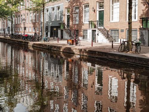 a reflection of buildings in the water of a canal at Sofitel Legend The Grand Amsterdam in Amsterdam