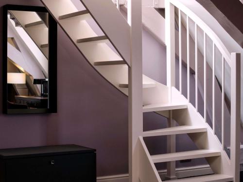 a staircase with white rails and a mirror at Sofitel Legend The Grand Amsterdam in Amsterdam