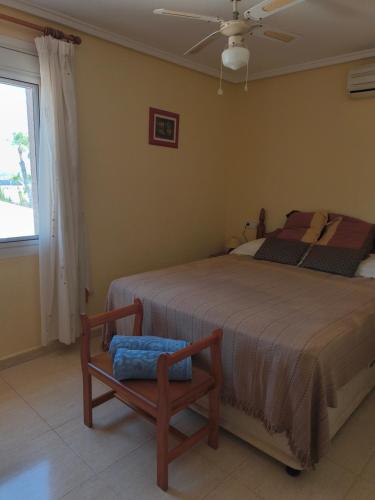 een slaapkamer met een bed, een stoel en een raam bij Villa with super swimming pool in Gran Alacant