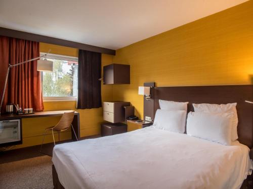 a hotel room with a large bed and a desk at Mercure Paris Porte de Pantin in Pantin