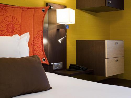 a hotel room with a bed with a lamp and a phone at Mercure Paris Porte de Pantin in Pantin
